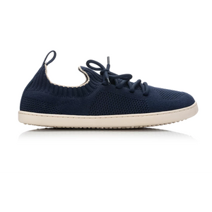 A navy blue knit slip-on sneaker with matching navy laces and a contrasting off-white sole, shown from a side profile on a white background.