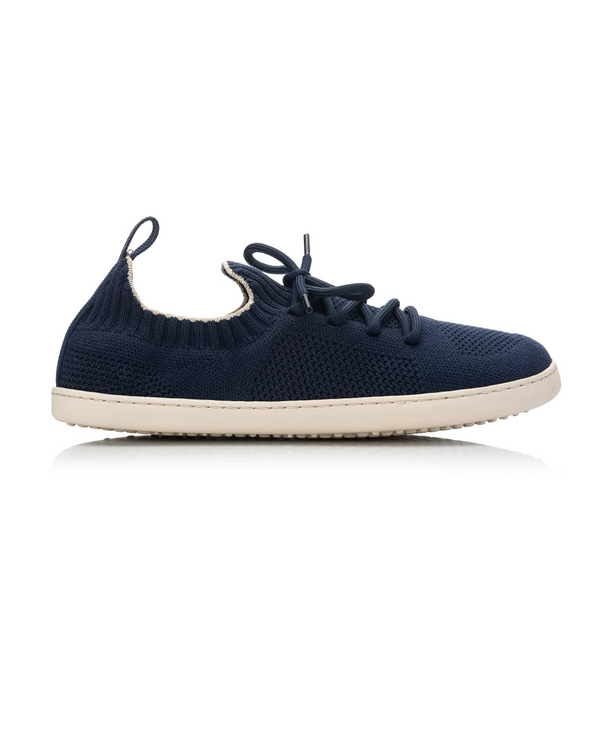 A navy blue knit slip-on sneaker with matching navy laces and a contrasting off-white sole, shown from a side profile on a white background.